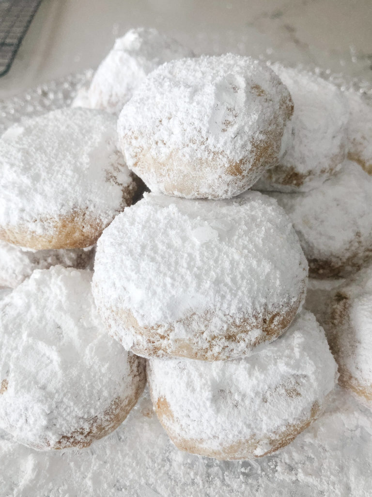 Greek almond cookies stacked on top of eachother and sprinkled with icing sugar