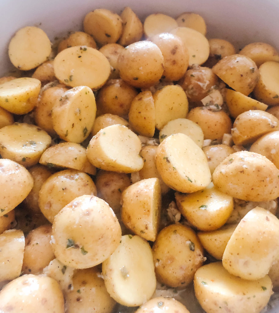 tiny potatoes cut in half with olive oil and seasoning spices