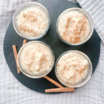 four small bowls of rice pudding displayed on a black board