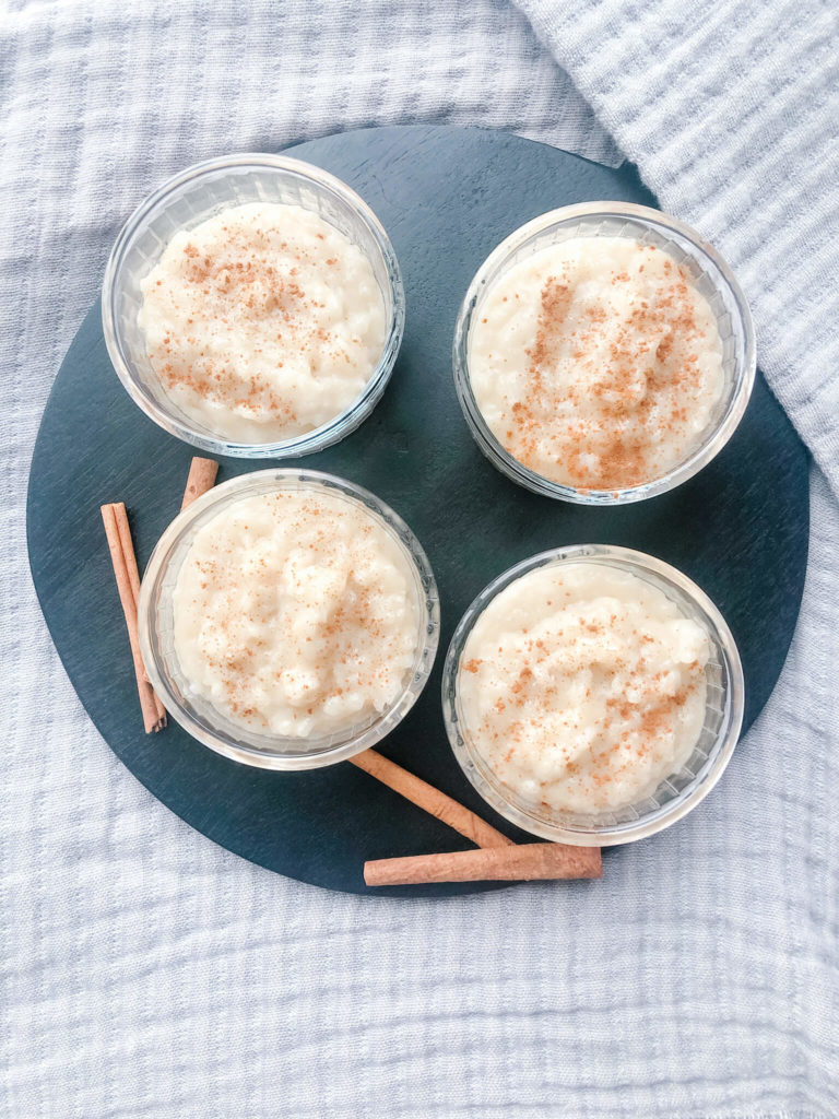 four small bowls of rice pudding displayed on a black board