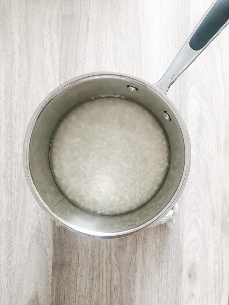 uncooked white rice with water in a saucepan