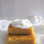 two pieces of Greek orange cake topped with whipped cream