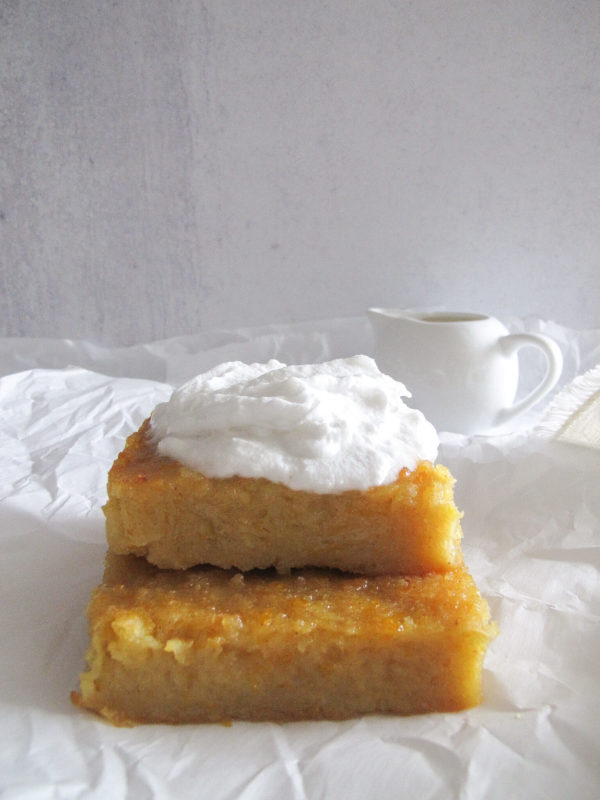 two pieces of Greek orange cake topped with whipped cream