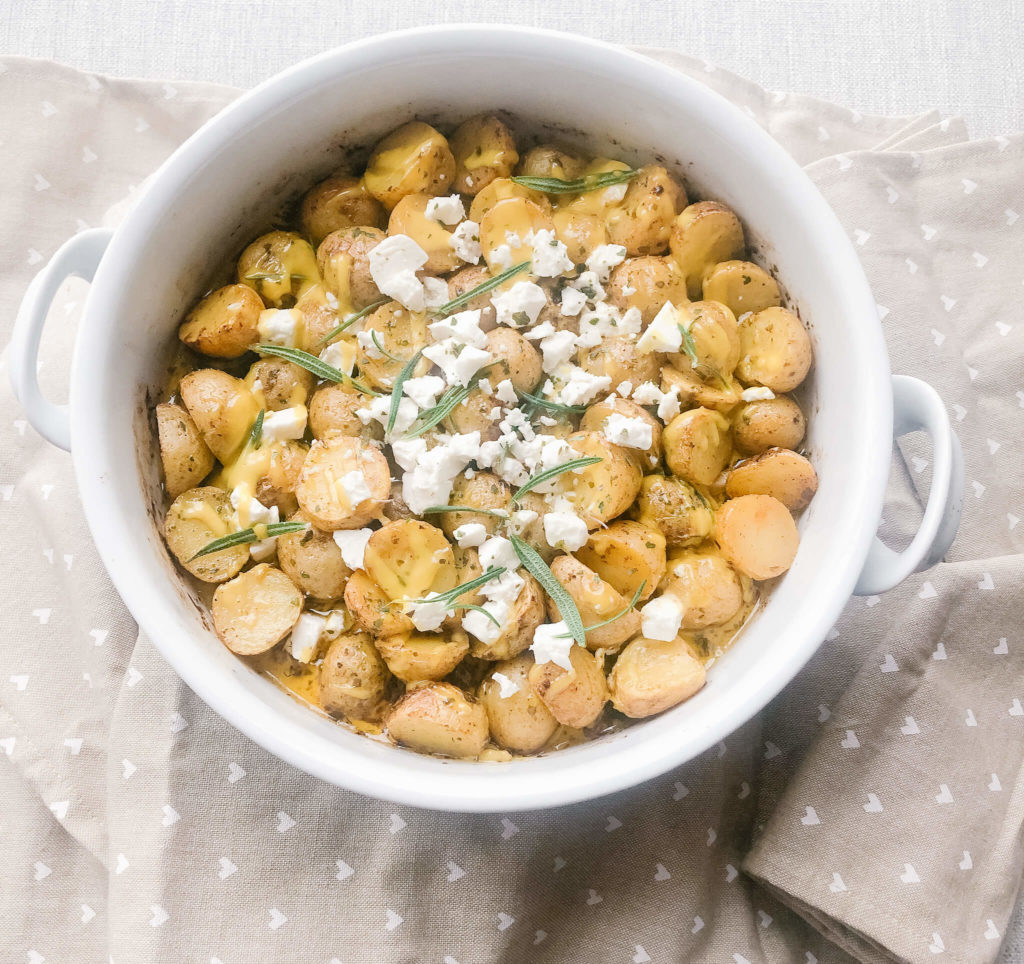 roasted tiny potatoes with seasonings, olive oil and crumbled feta in a white baking dish.