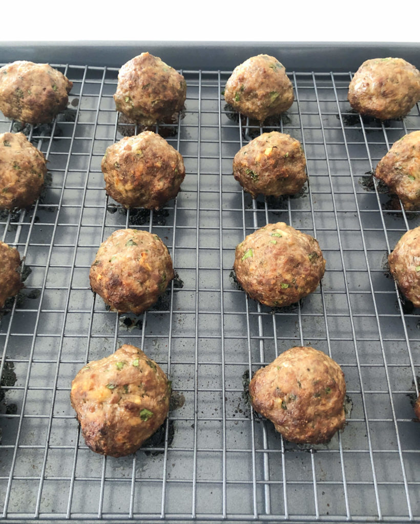 cooked meatballs on a cooling rack and baking sheet