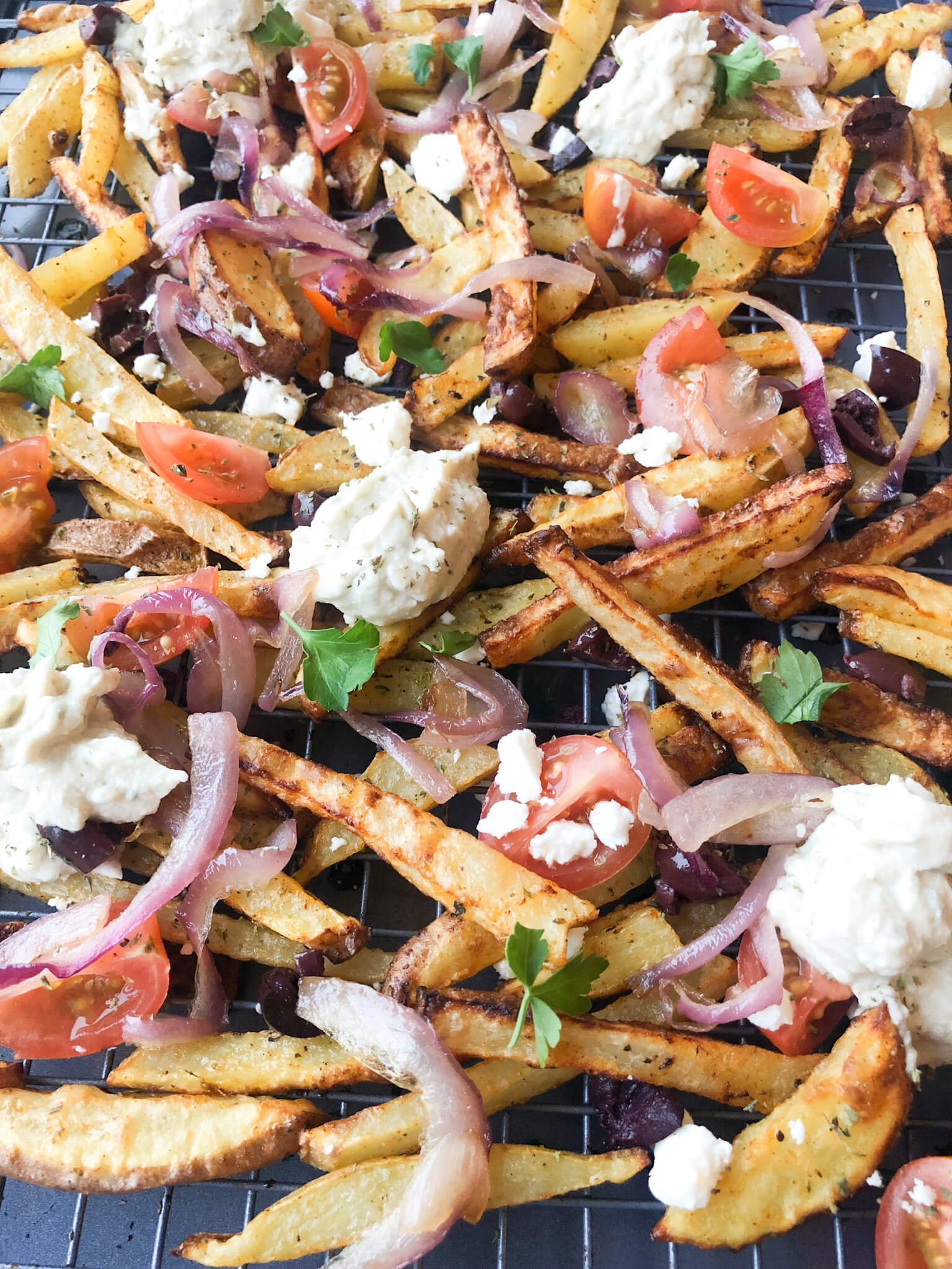 baked greek fries topped with feta, tomatoes, olives, and oregano