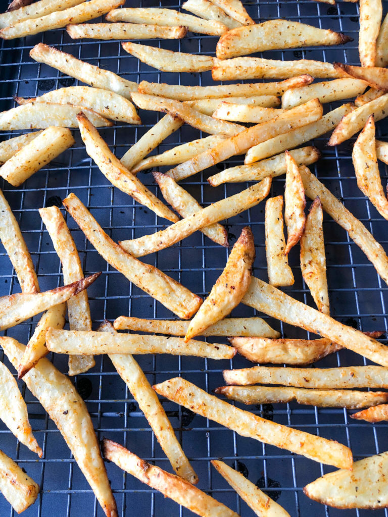 Cooked homemade fries with greek seasoning on a baking sheet