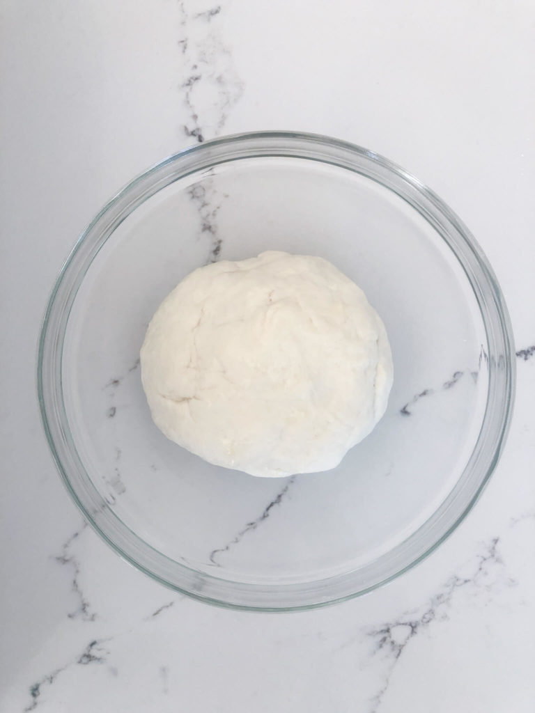 a ball of pita bread dough in a clear bowl