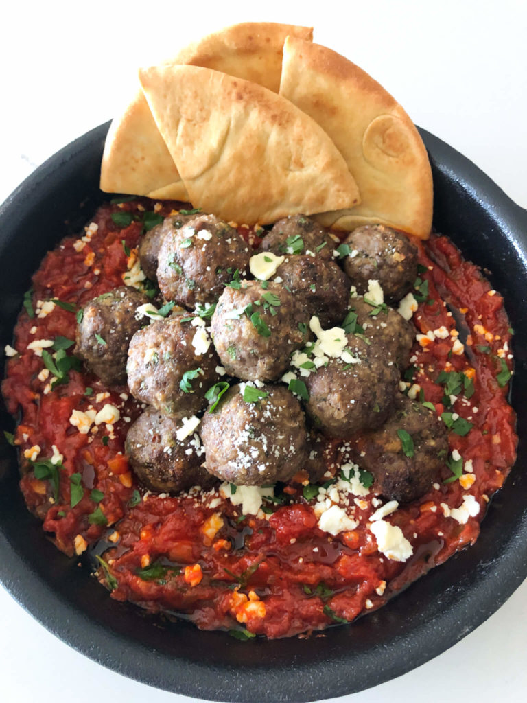 cooked meatballs in marinara sauce with pita bread in a cast iron skillet