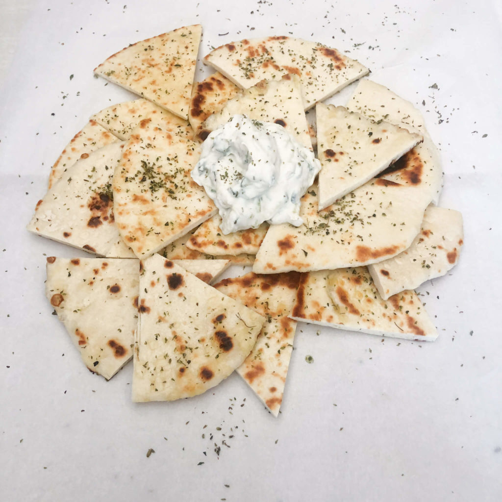 sliced pita bread triangles topped with tzatziki.