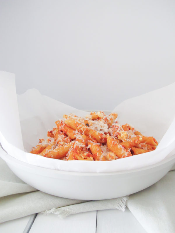 A bowl of penne pasta with pink pasta sauce topped with crumbled feta and parmesan cheese