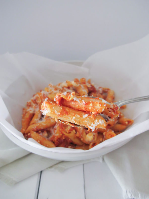 penne pasta with pink pasta sauce on a spoon sprinkled with parmesan cheese