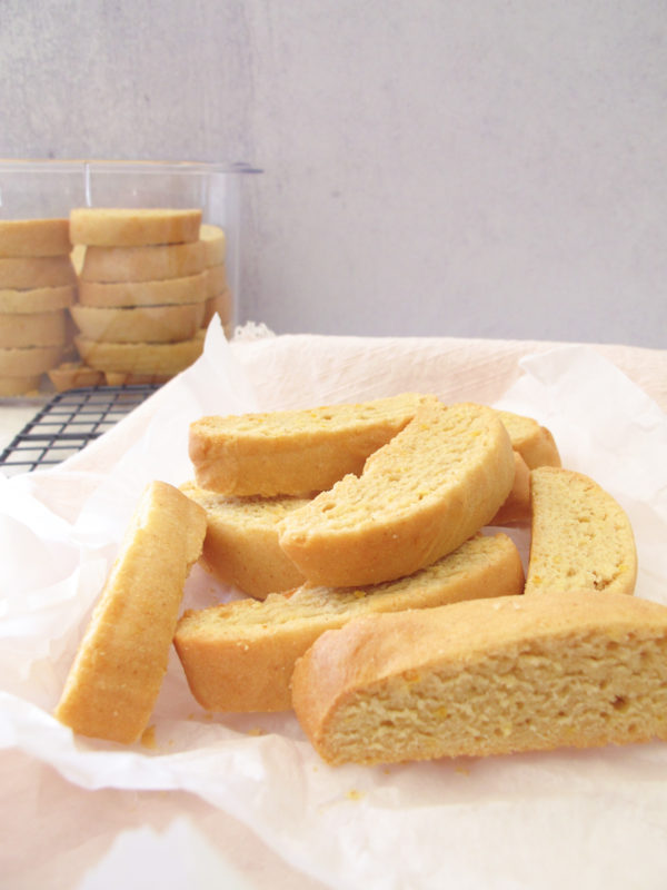 A few pieces of baked biscotti on parchment paper and a cooling rack.