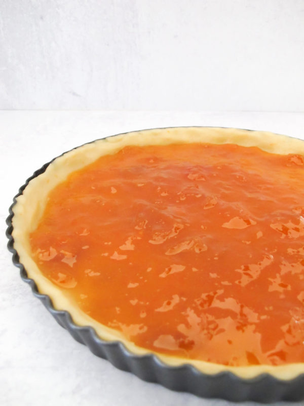 Shortbread crust in a tart pan with apricot jam filling.