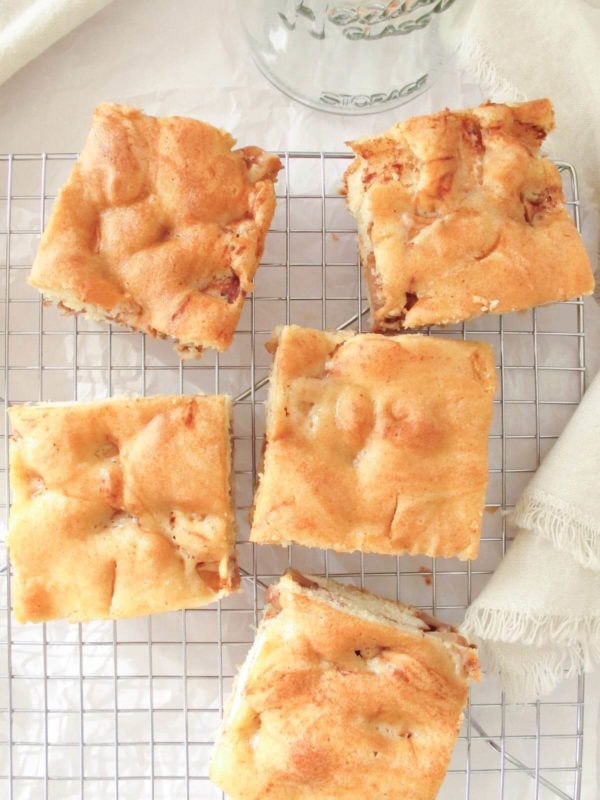 square pieces of greek apple cake on a cooling rack.