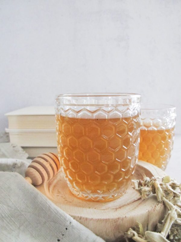 Greek mountain tea in a clear tea glass on a wooden plate.