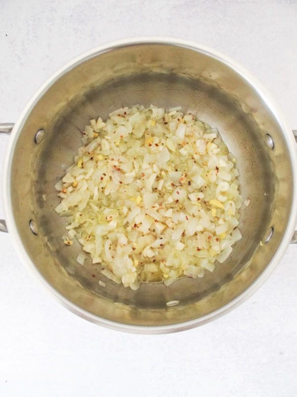 sautéed diced white onions, ginger, garlic, and chili flakes with olive oil in a large pot.
