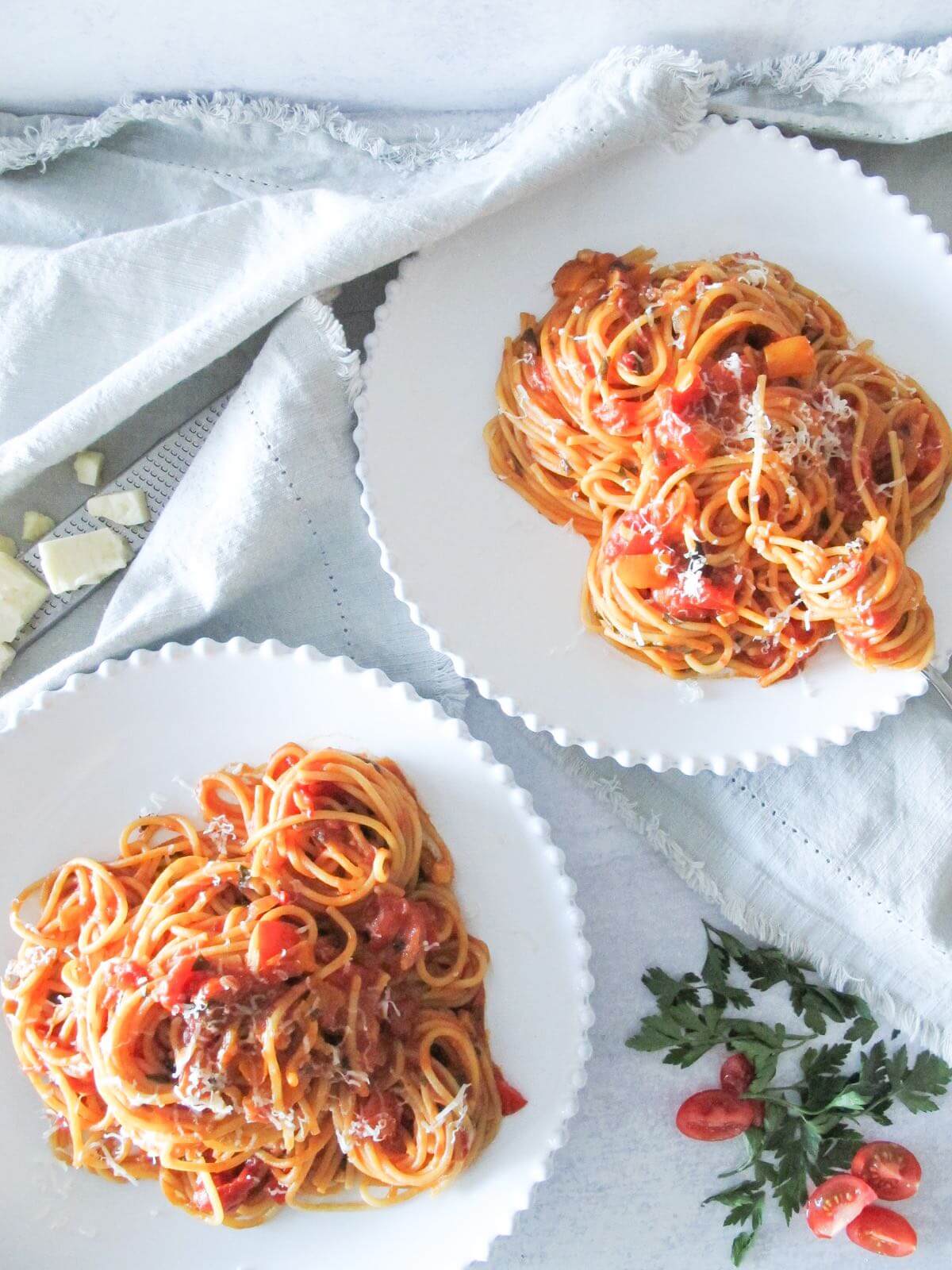 two plates of spaghetti with spicy tomato sauce on a linen napkin.