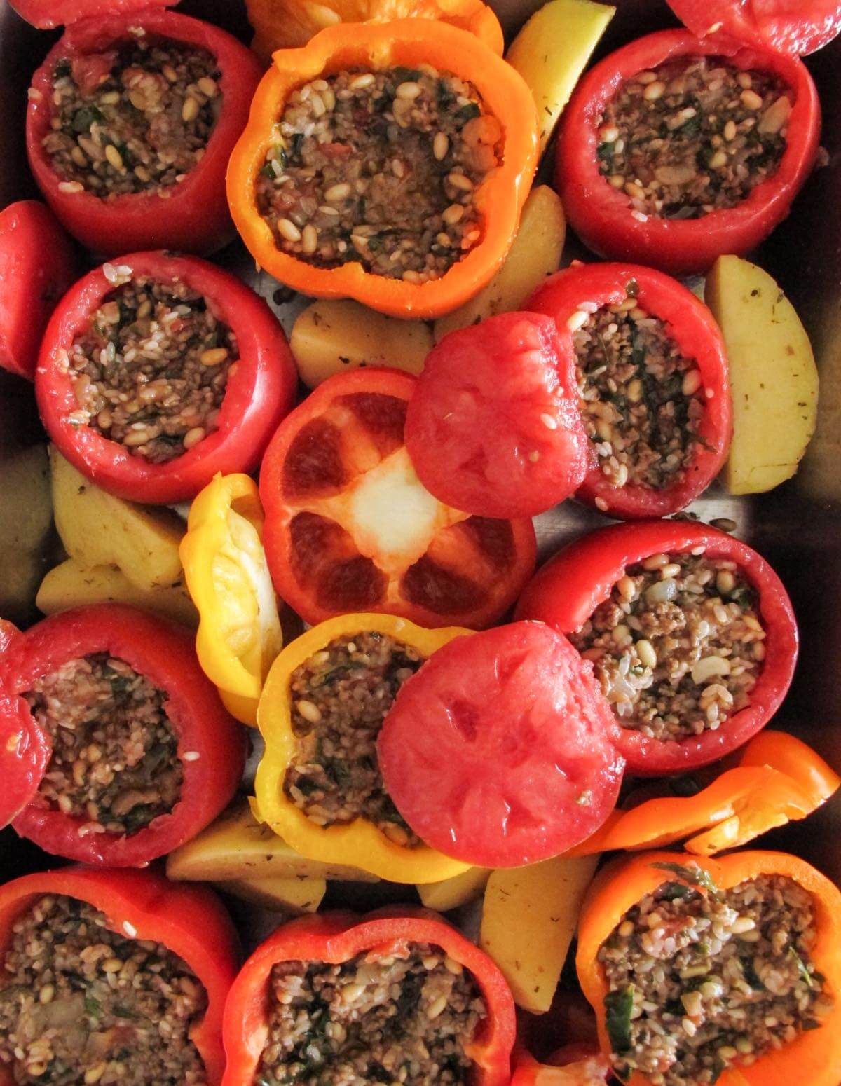uncooked Greek stuffed peppers and tomatoes in a baking dish.