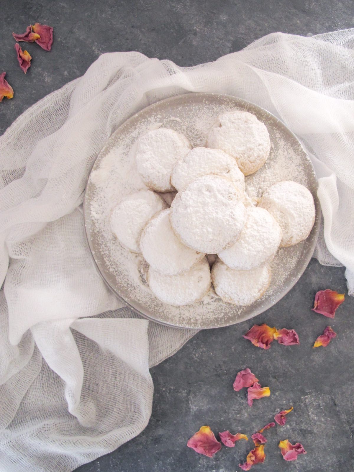 vegan kourabiedes (greek butter cookies) with icing sugar on a grey plate.