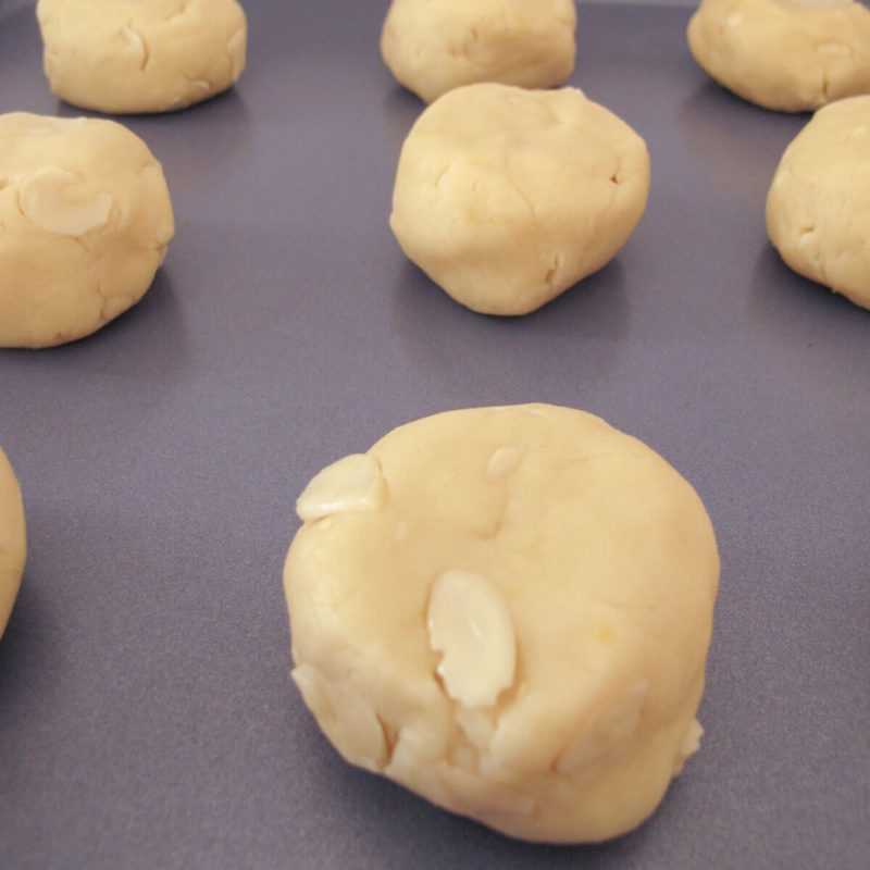 unbaked kourabiedes on a baking sheet.