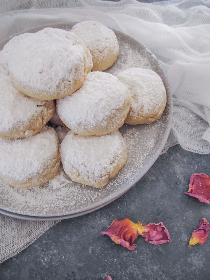 vegan kourabiedes with icing sugar on a grey plate.