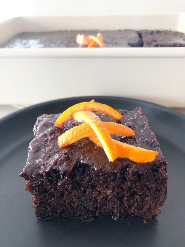 a piece of Greek chocolate orange cake on a black plate.
