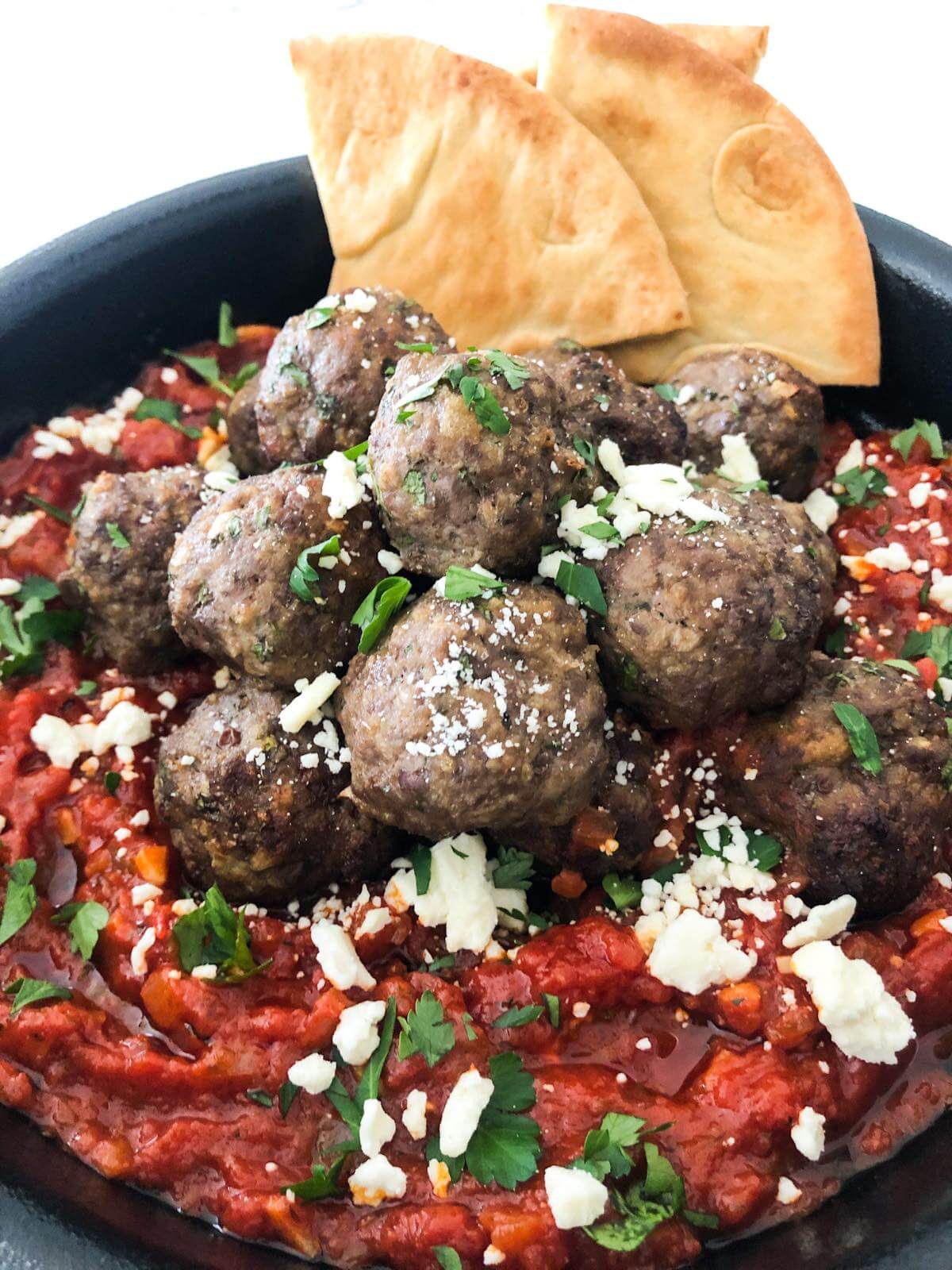 meatballs in tomato sauce with feta cheese and fresh basil.
