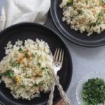 two plates of greek rice with diced parsley and fresh dill.