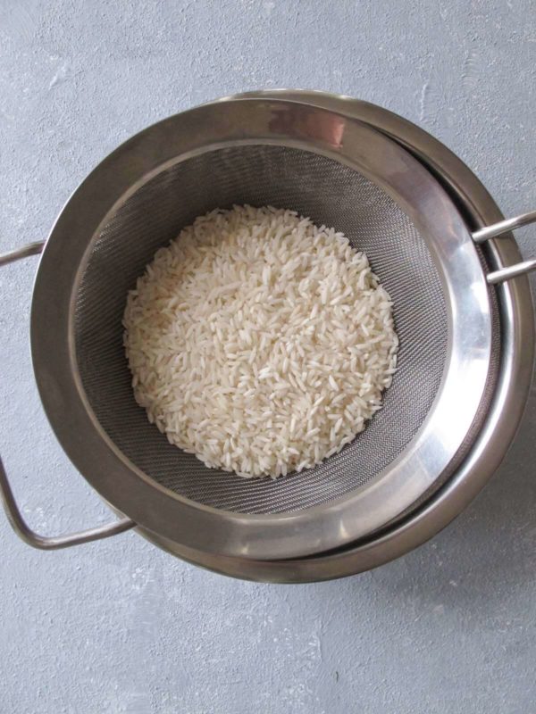 white rice in a stainless steel mesh strainer.