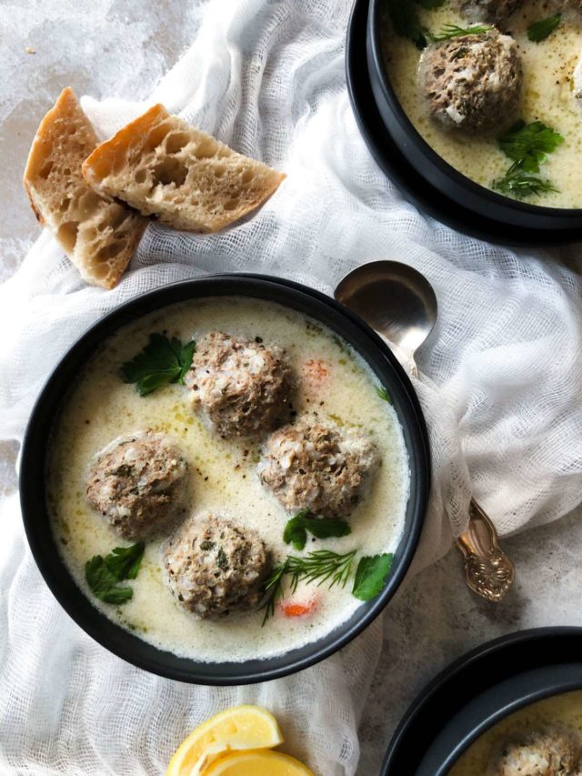 Greek meatball soup (youvarlakia) in a black bowl with a spoon.