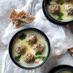 Greek meatball soup with avgolemono (youvarlakia) in a black bowl with fresh bread.