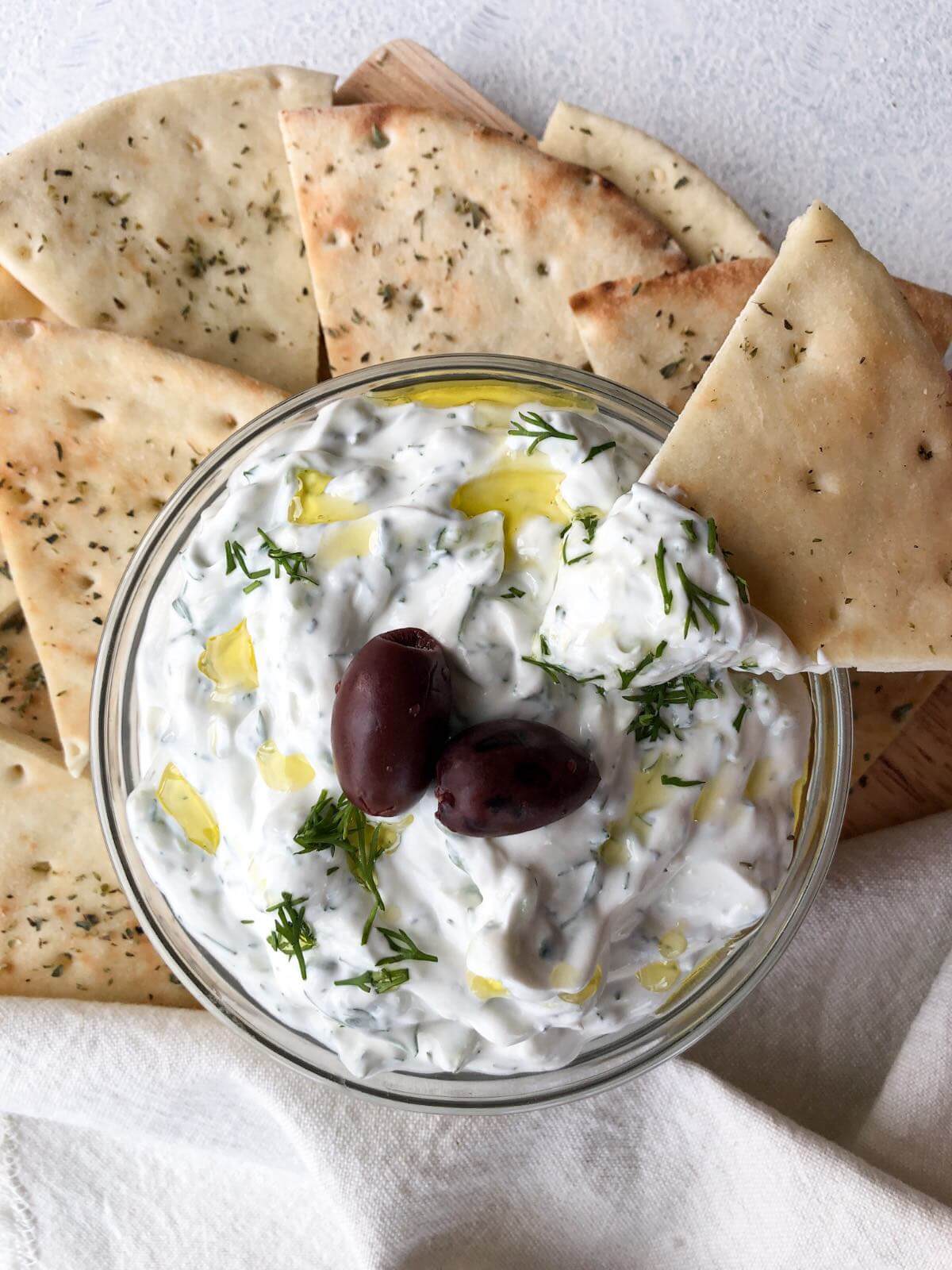 Tzatziki made with sour cream in a bowl with pita bread dipped in.