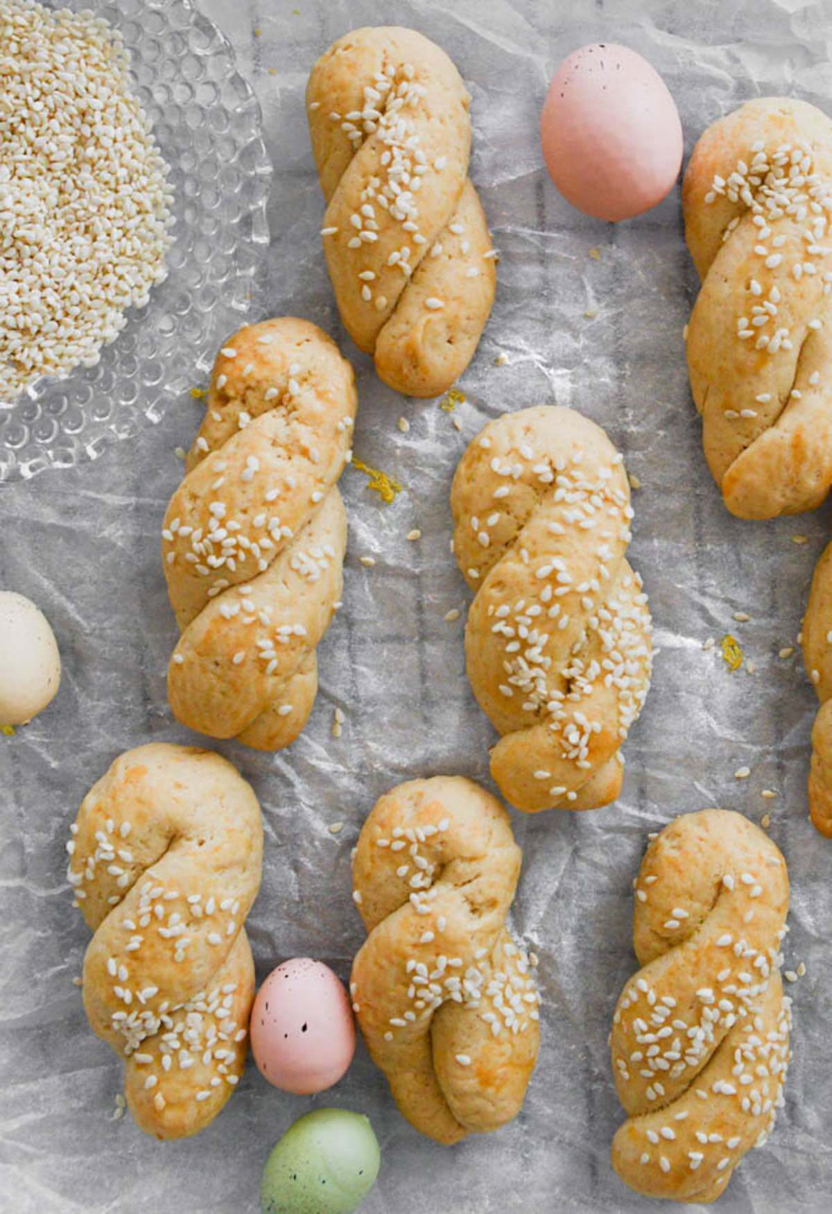 Greek easter cookies (koulourakia) with sesame seeds on white parchment paper.