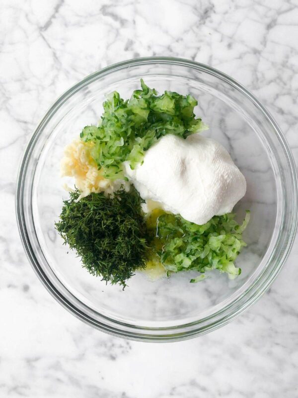 strained sour cream, strained shredded cucumbers, fresh dill, olive oil, salt, lemon juice, and white wine vinegar in a large glass bowl.