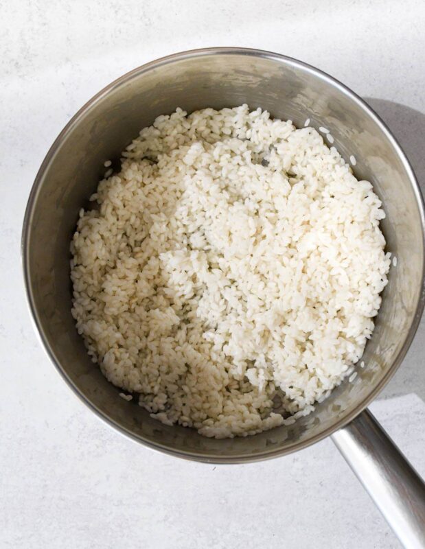 white rice partially cooked in a small saucepan.