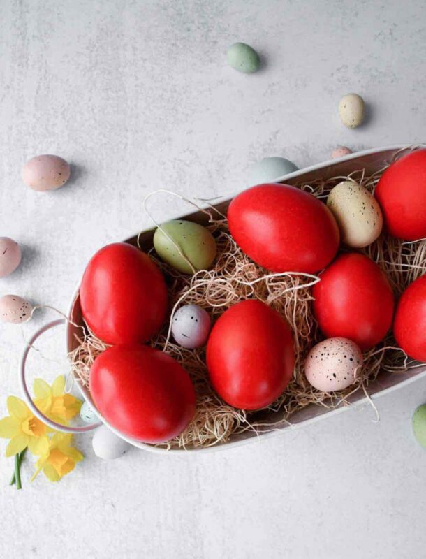 Greek red easter eggs in a white basket with mini coloured eggs.
