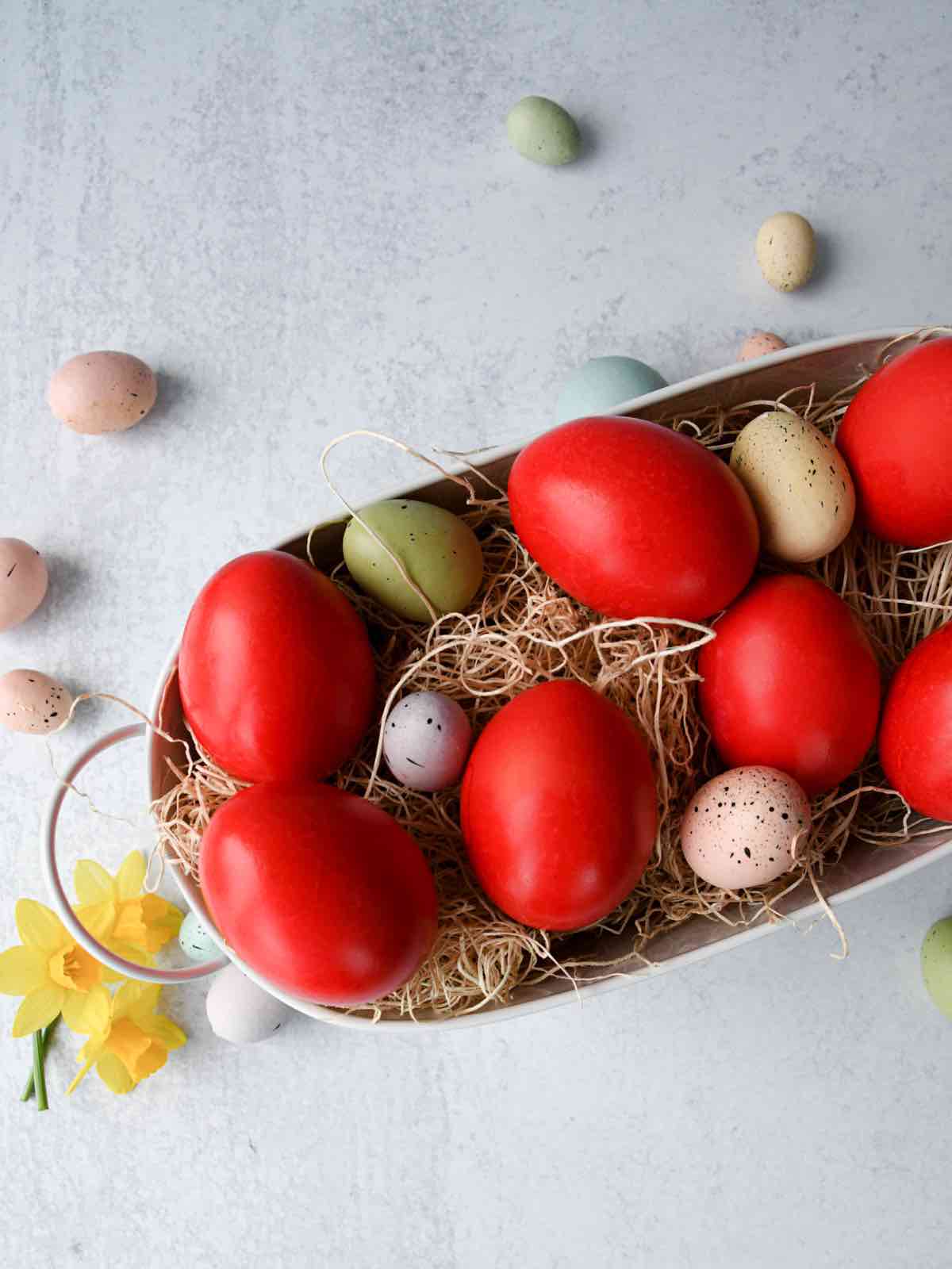Greek red easter eggs in a white basket with mini coloured eggs.