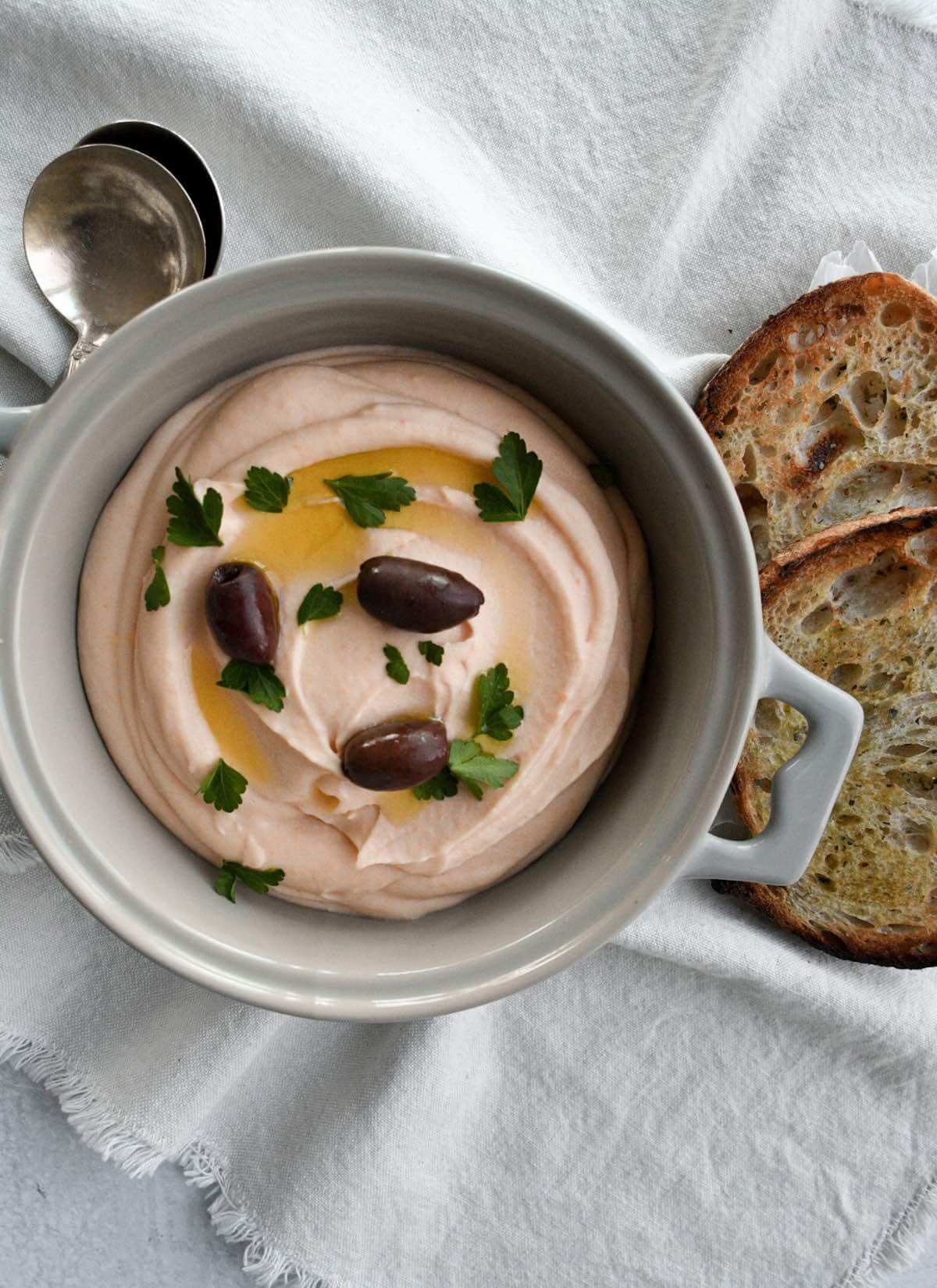taramasalata dip in a light grey bowl with a side of bread.