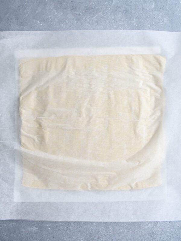one rolled out sheet of puff pastry on white parchment paper.