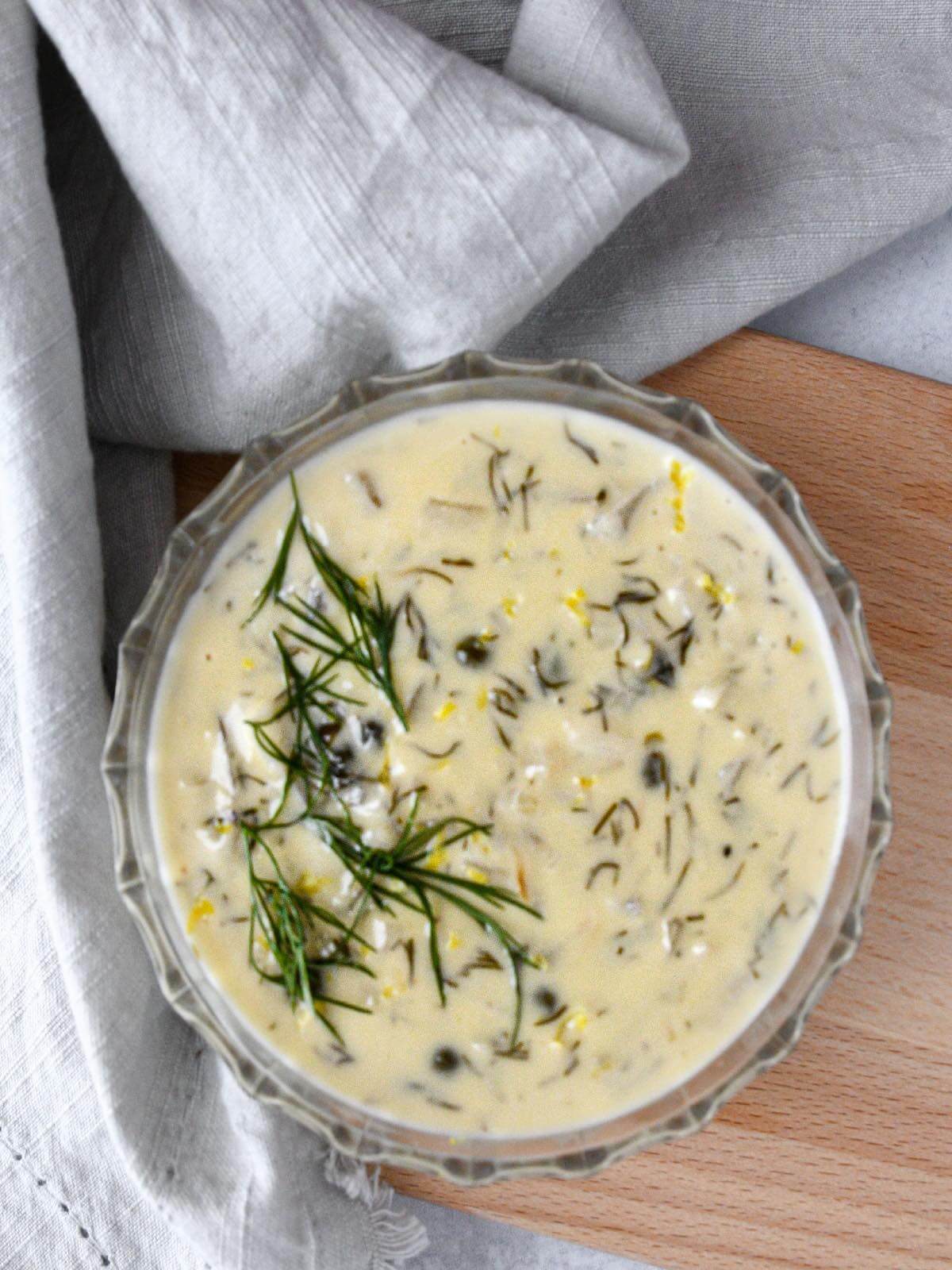creamy dill sauce in a clear small glass bowl with fresh dill and lemon zest on top.