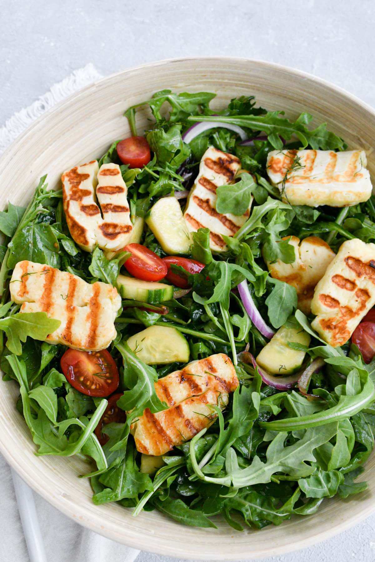 Halloumi cheese salad with spring mix, arugula, cherry tomatoes, fresh dill, sliced onions, and an olive oil and balsamic glaze dressing.