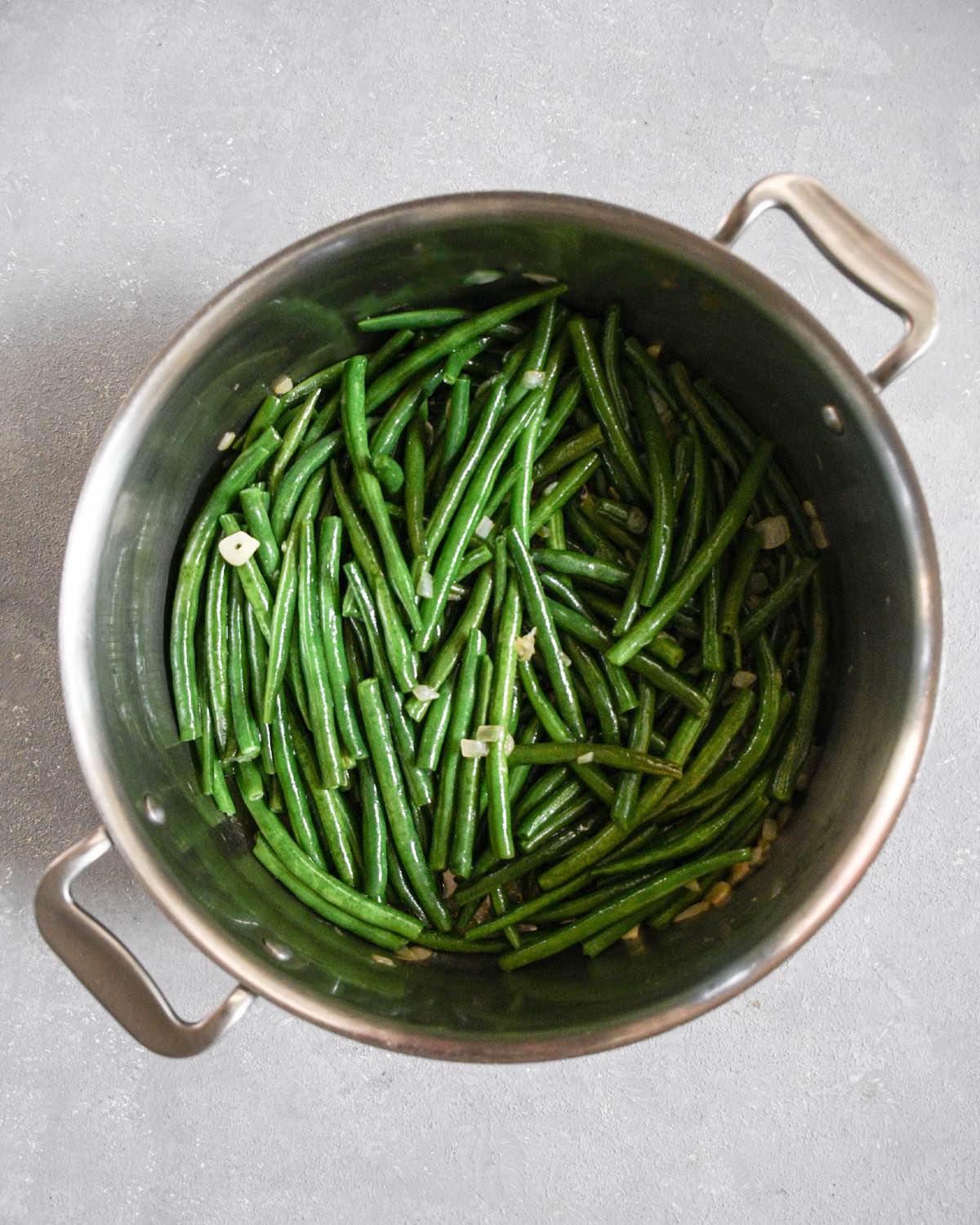 green beans (fasolakia) cooking in a large pot with garlic and onions.