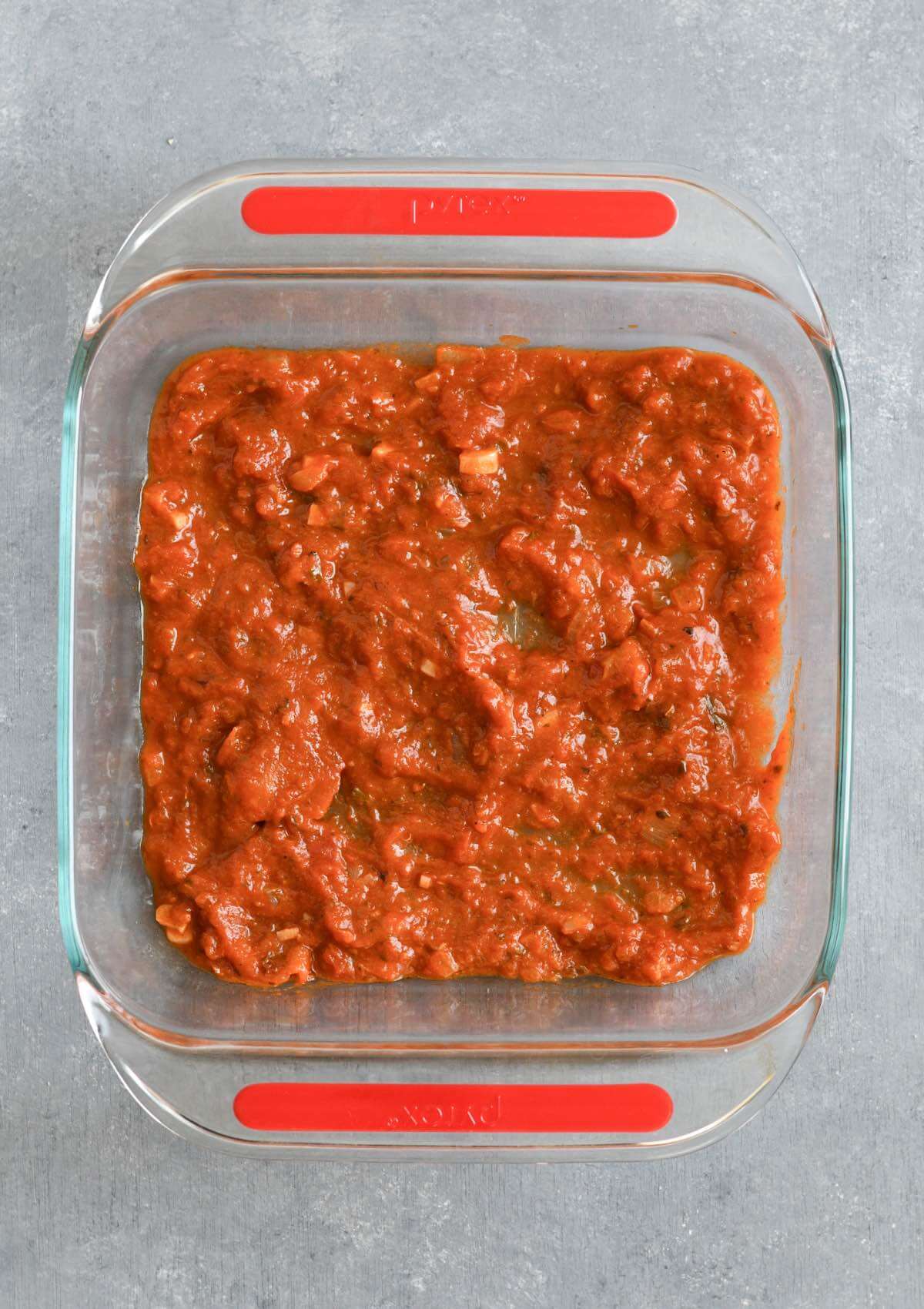 tomato sauce in the bottom of a 8" x 8" baking dish.