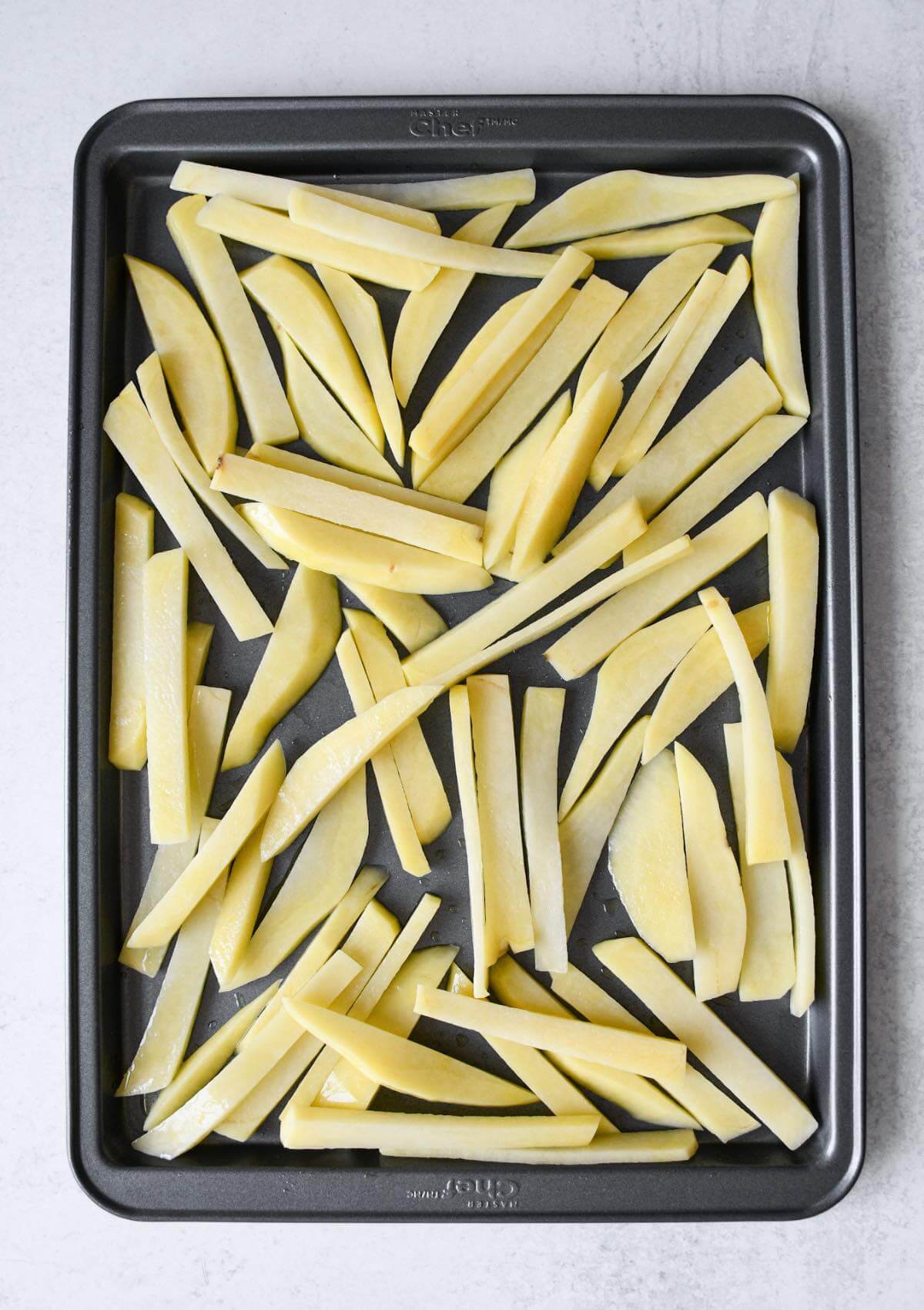 sliced uncooked fries on a baking sheet.