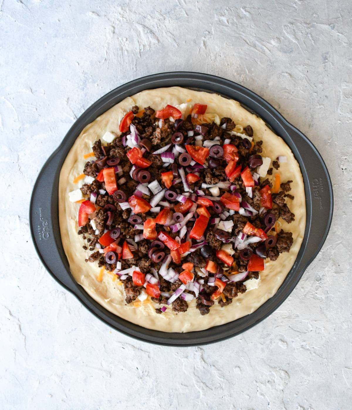 homemade pizza with garlic butter, mixed cheese, cooked ground beef, tomatoes and red onions.