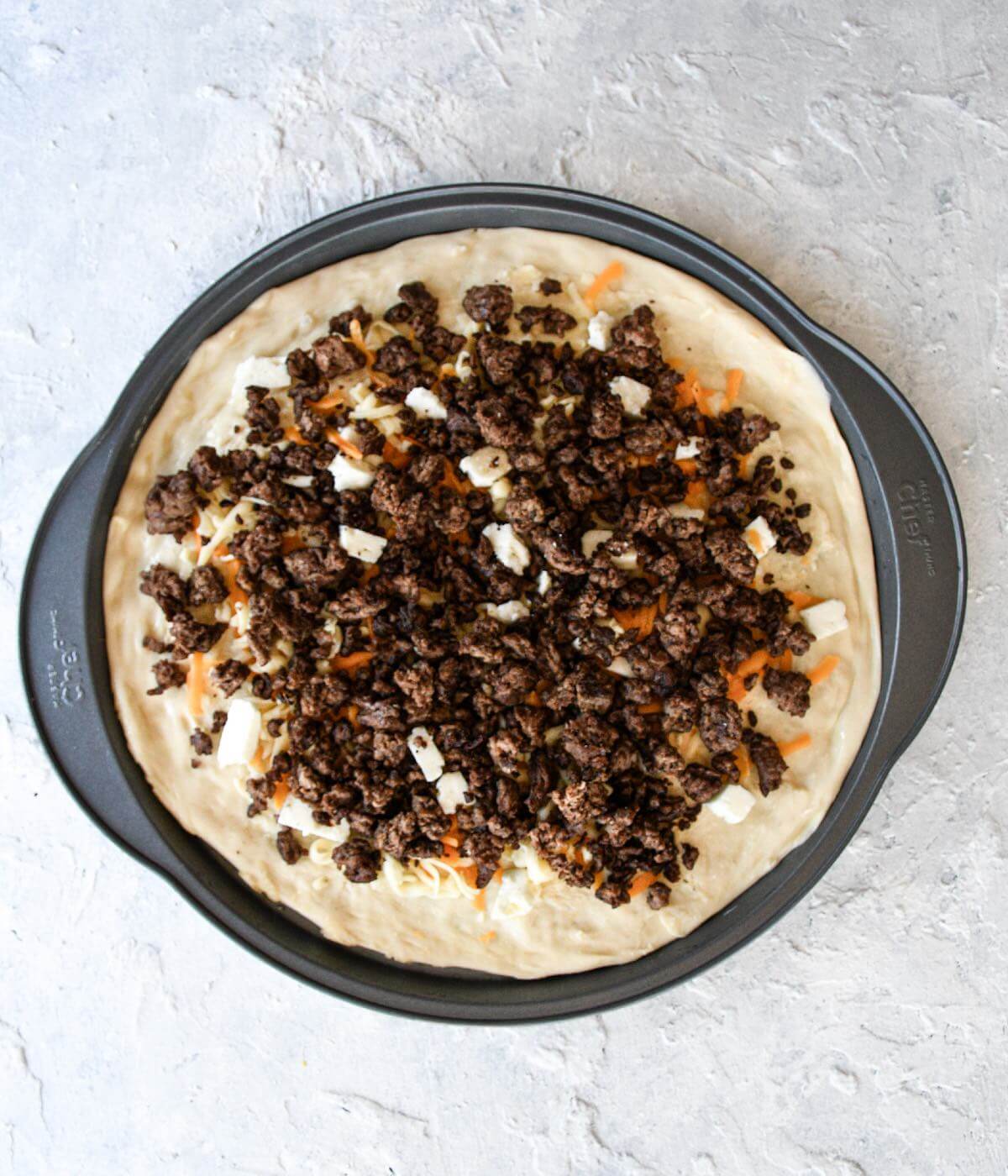 homemade pizza with garlic butter, mixed cheese, and cooked ground beef.