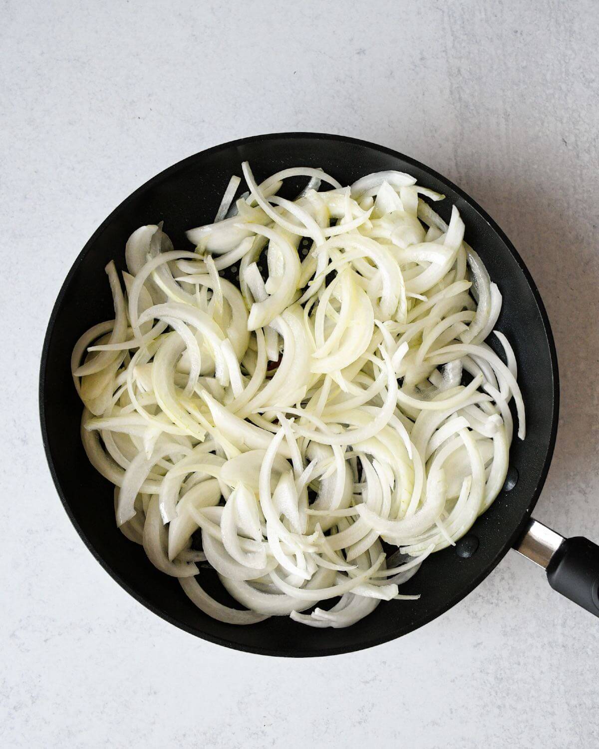 sliced white onions in a frying pan.
