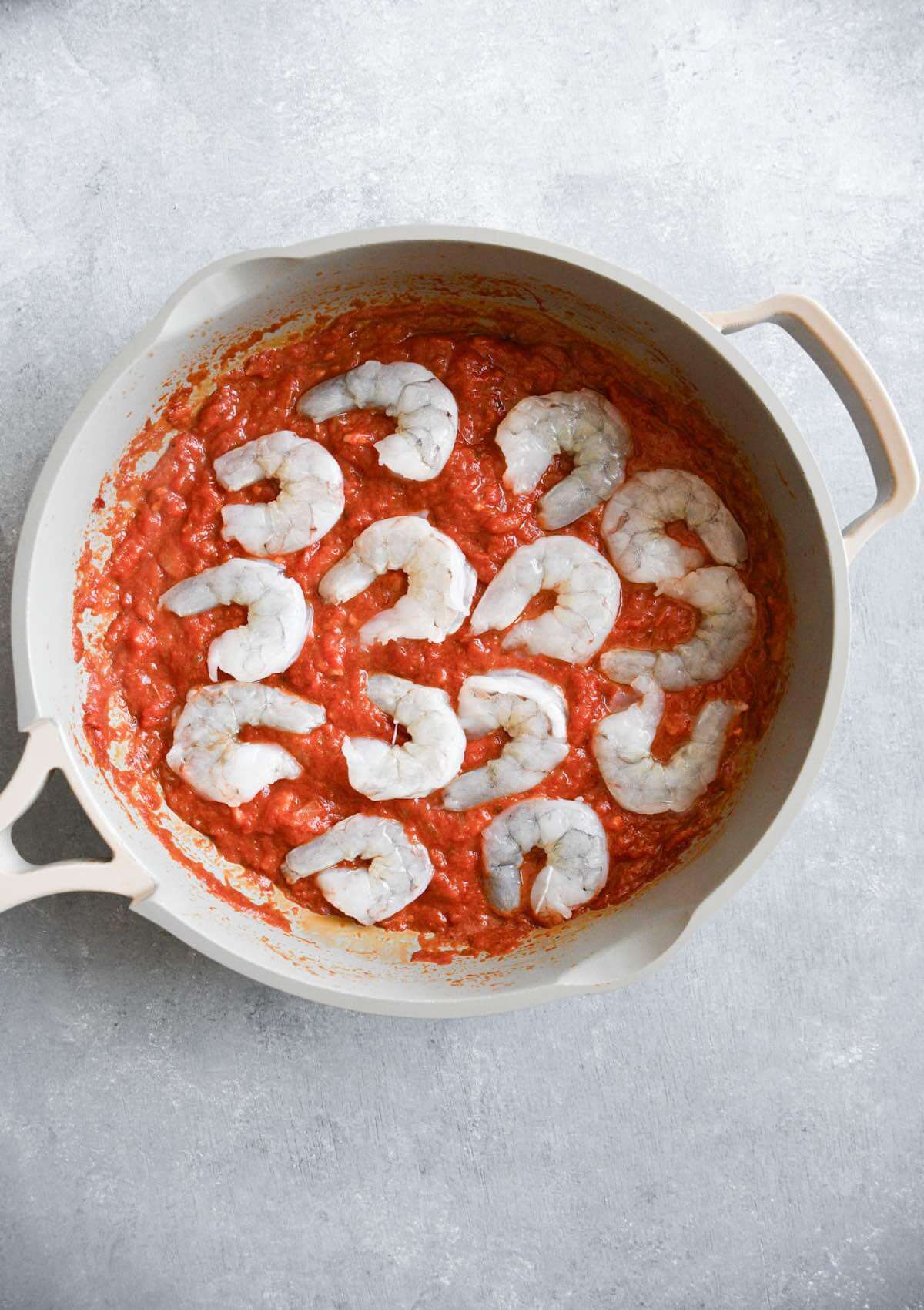 raw shrimp in a frying pan with tomato sauce.