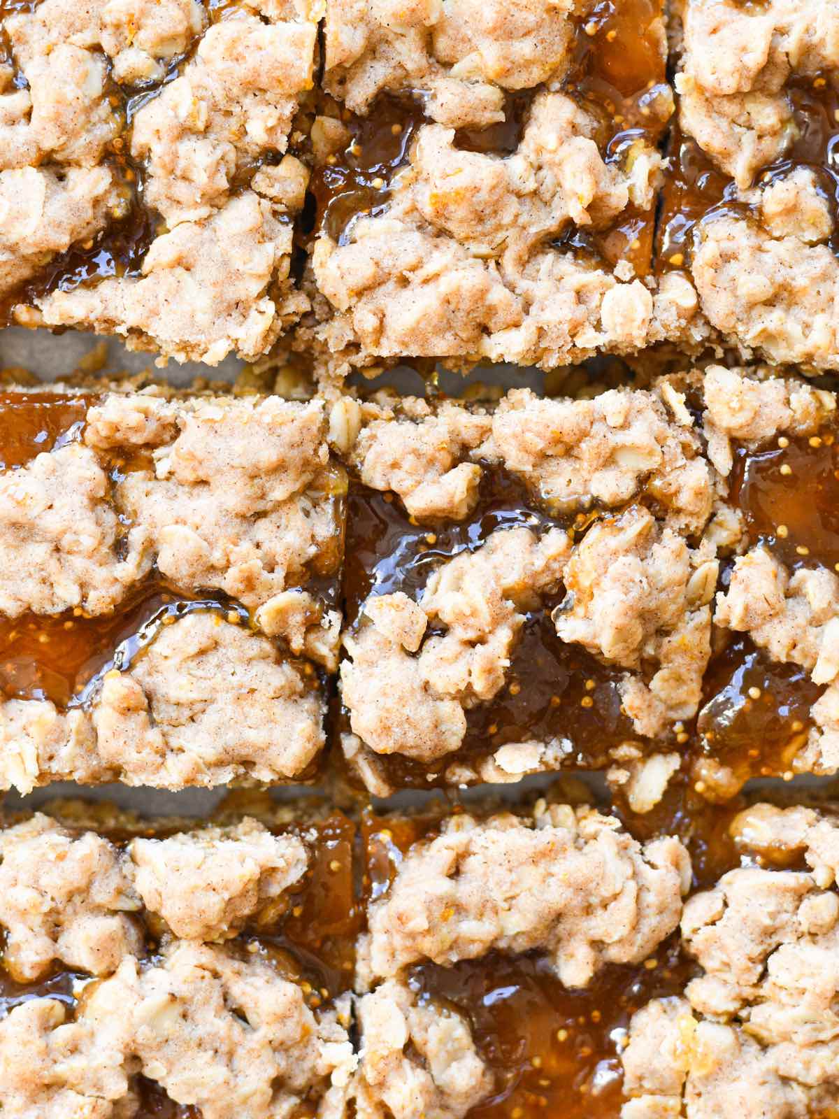 oatmeal fig jam bar squares with oat crumble on white parchment paper.
